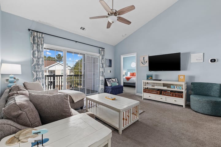 Cozy living room has plenty of seating and a smart TV. The ottoman in the corner also folds out to a twin bed.