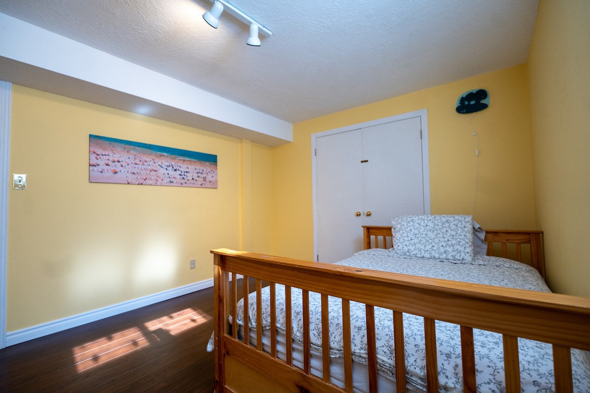 Acogedora habitación en el sótano con una litera (doble abajo, individual arriba), un armario, grandes ventanales para la luz natural y una gran puerta que conecta con la sala de estar compartida del sótano. 