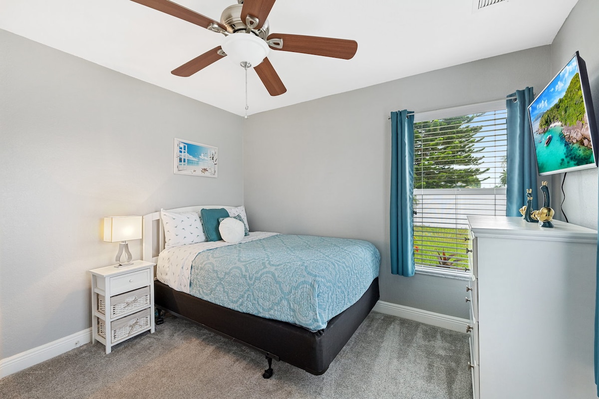 Cozy guest bedroom with soft tones, smart TV, and relaxing natural light.