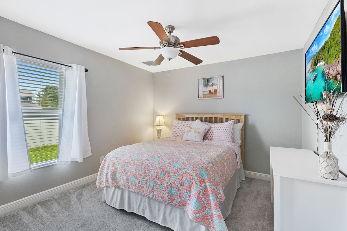 Charming guest room with cozy bedding, smart TV, and plenty of natural light.