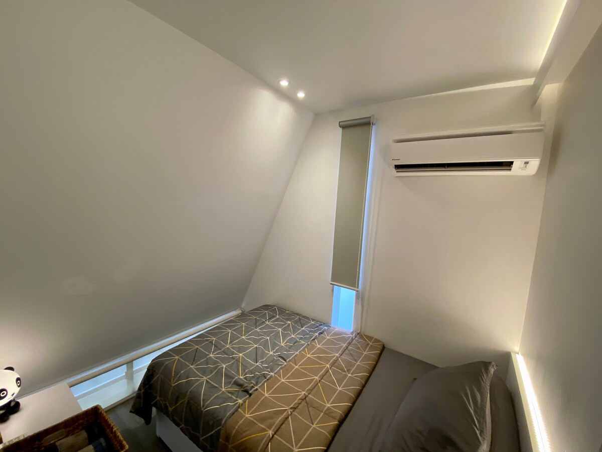 Una habitación acogedora y compacta con techo inclinado y una cama individual de 120 cm. Ideal para un refugio tranquilo en un espacio único.