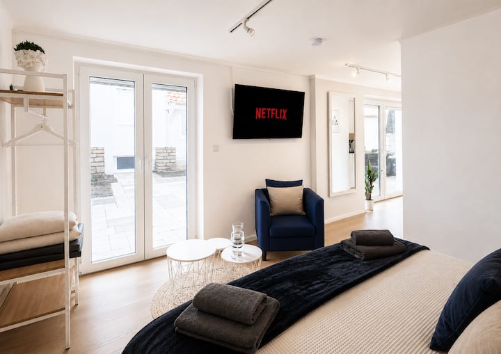 Entspannen & genießen: Der helle Wohn- und Schlafbereich lädt zum Wohlfühlen ein. Machen Sie es sich im gemütlichen Sessel bequem, genießen Sie Netflix oder lassen Sie den Tag entspannt ausklingen – ein schöner Rückzugsort für Ihre Auszeit.