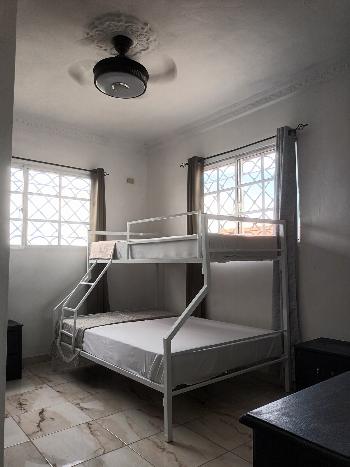 Táto izba ponúka poschodovú posteľ s manželskou posteľou Queen a samostatnú posteľ na poschodí, ktorá je ideálna pre rodiny alebo priateľov. Má vlastnú kúpeľňu, stropný ventilátor na príjemnú cirkuláciu vzduchu a pohodlné a funkčné prostredie na oddych.