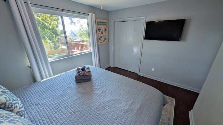 Chambre à coucher à l'étage avec beaucoup de lumière naturelle. Nouveau téléviseur de 43 po ajouté à l'automne 2025