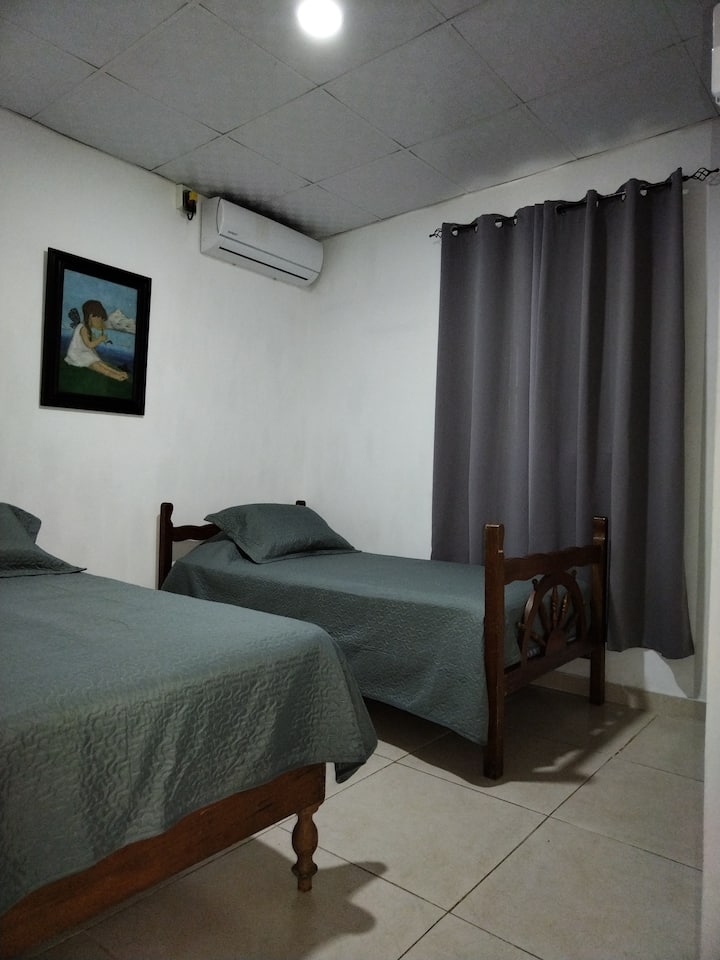 Segunda habitación, con ventana vista a la terraza y jardín, aire acondicionado, dos camas twin o 3/4, área para colgar ropa y ganchos.