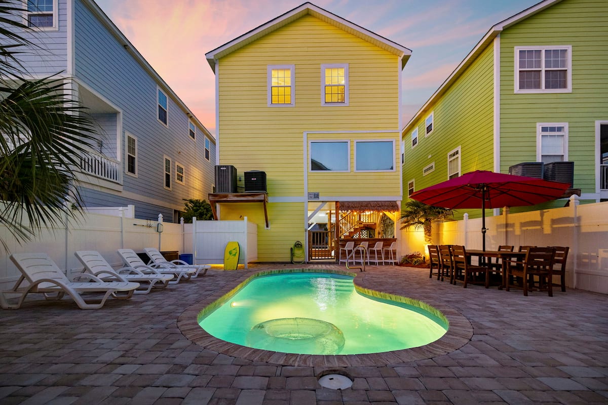 End the beach day right here, with the pool glowing under the string lights, the tiki bar open, and the kind of evening nobody wants to leave early.