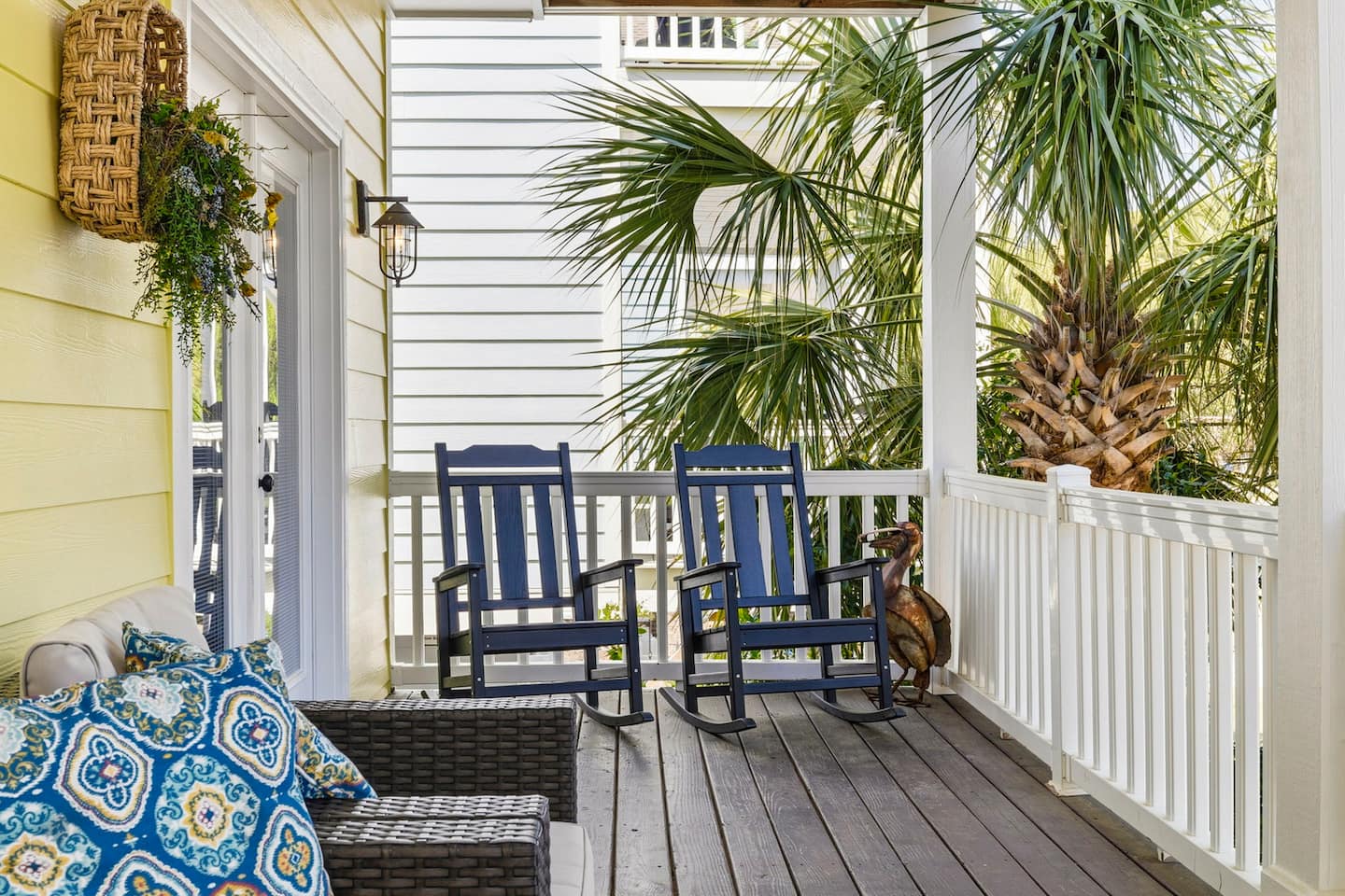 Rock on the navy front-porch chairs. Two people, coffee cups, palm trees, and nowhere to be until the beach calls you down the block.