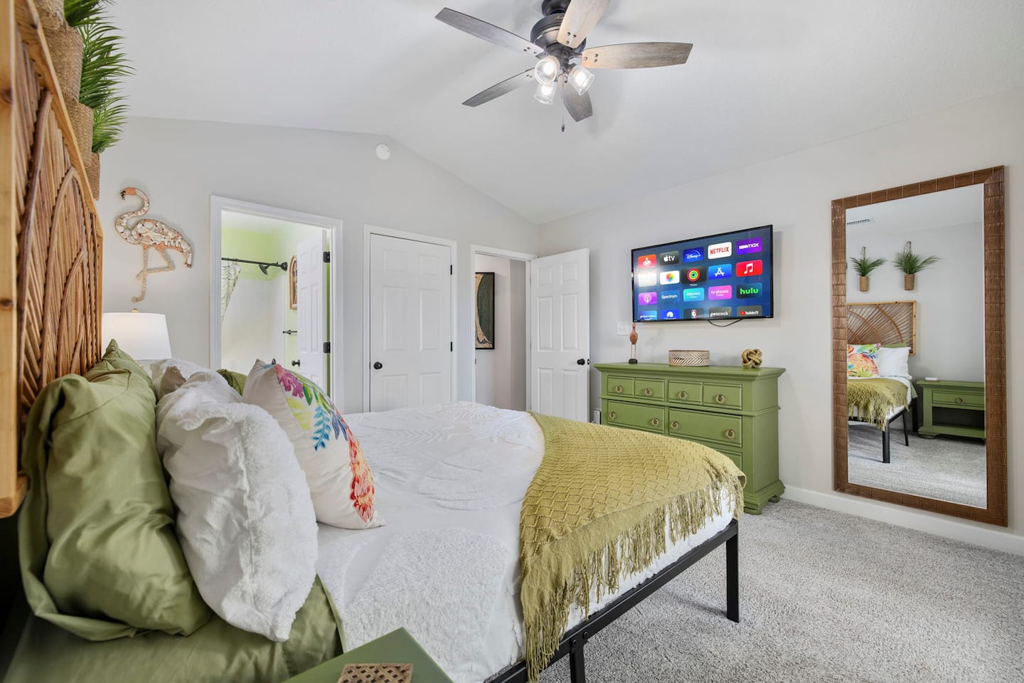 See the full flamingo room from this angle. Smart TV on the wall, full-length mirror, and the en-suite door confirming your private bathroom.
