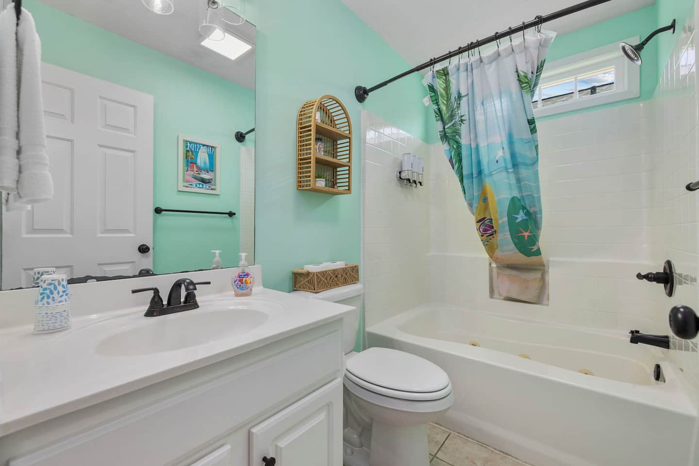 Use the hall bathroom near the bunk room. Fresh mint, tub-shower combo with a tropical beach curtain, vanity stocked and ready for your whole crew.