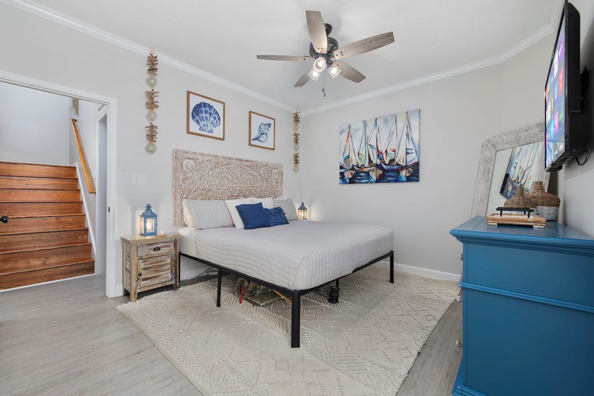 Sleep in the main-floor king: carved wood headboard, private en-suite, and no stairs in the morning for whoever wins this room in the group assignment.