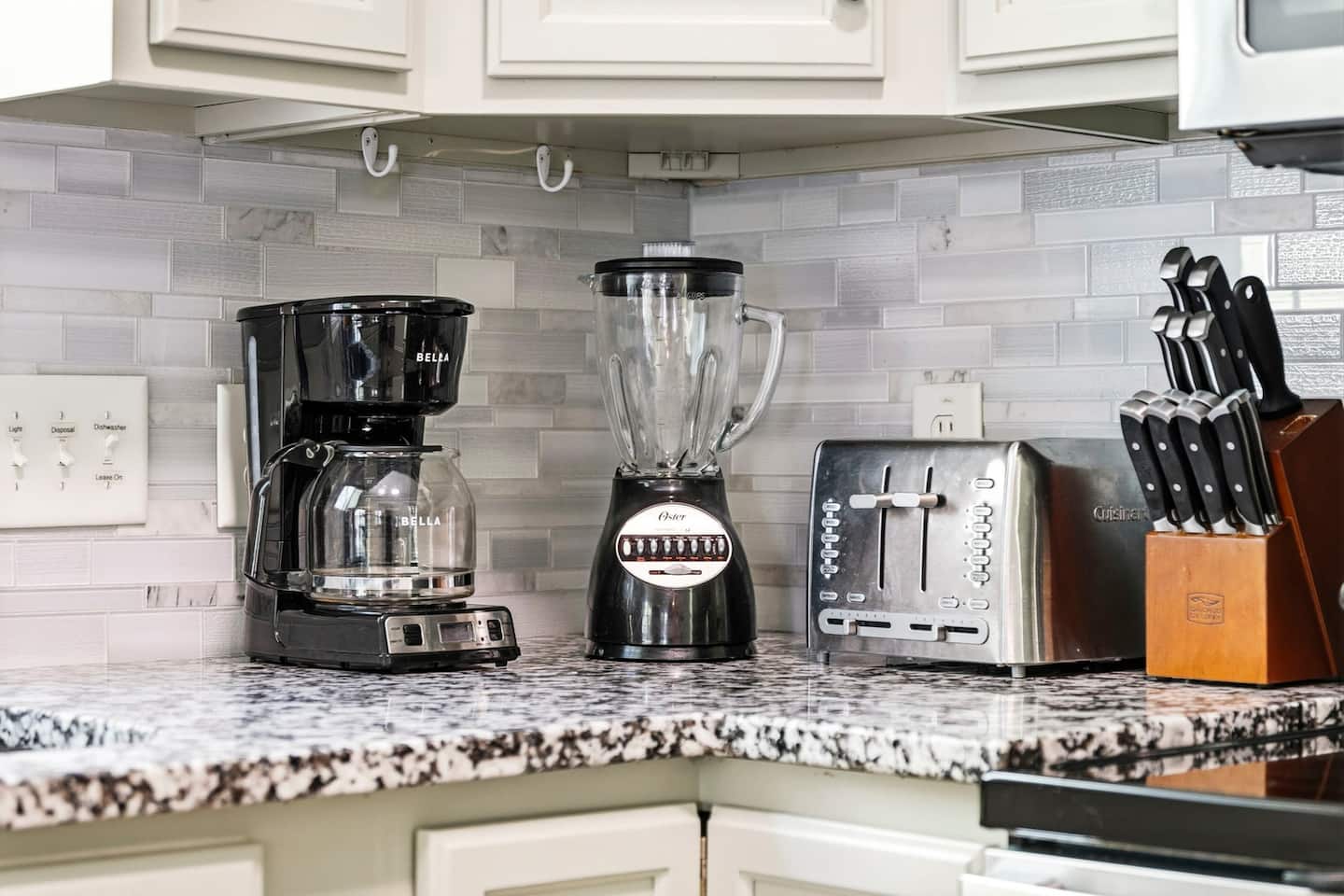 Find everything on the kitchen counter and ready to use: drip coffee maker, blender, toaster, and a full knife block on the granite countertop.