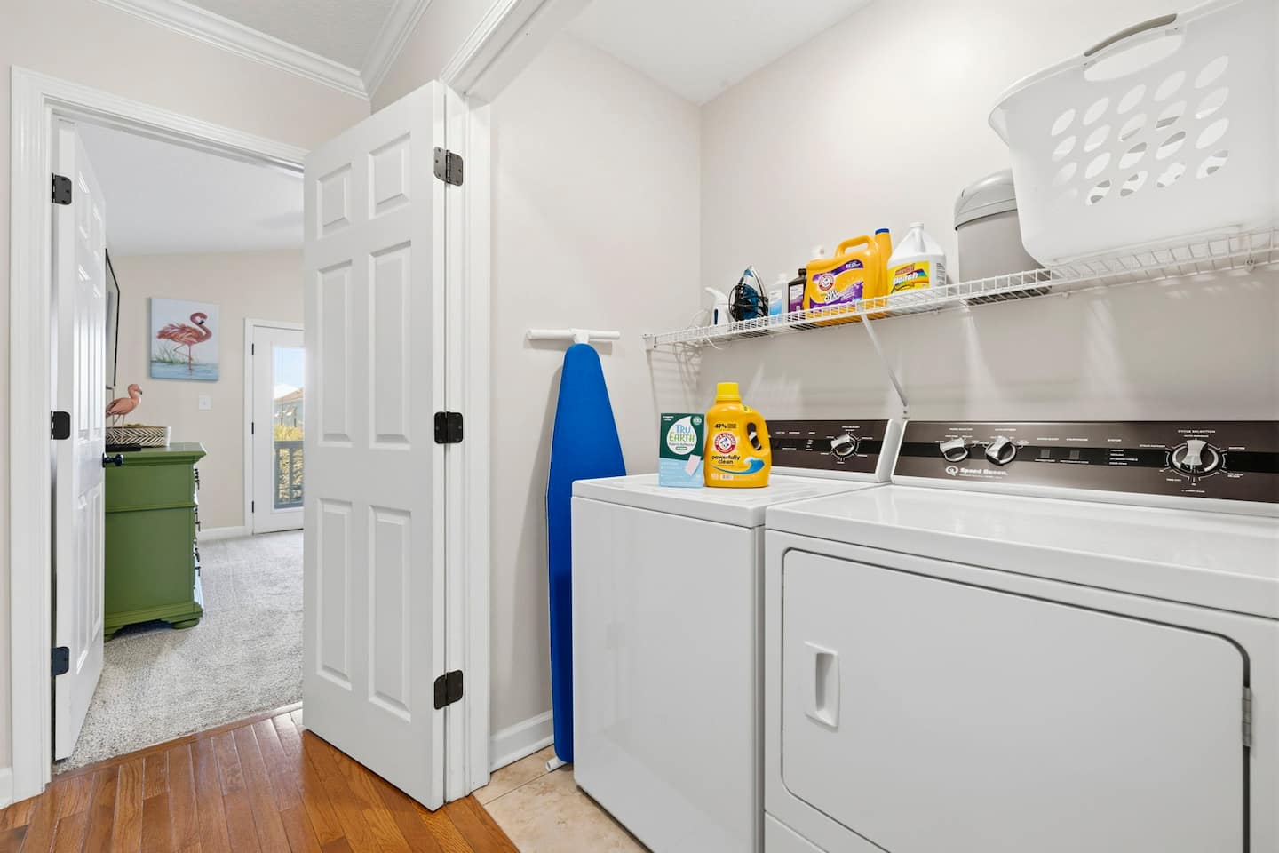 Toss a load in without leaving the property. Full-size washer and dryer in the dedicated laundry room, detergent on the shelves, ironing board on the wall.