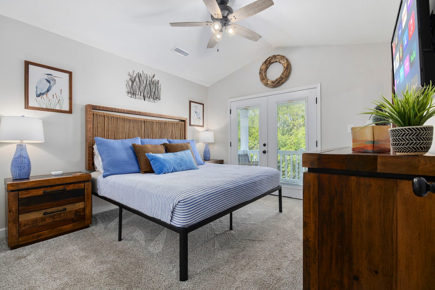 Claim the hand-woven headboard king room for the couple who wants balcony access. French doors open to the upper deck, heron art on the wall, a king bed ready.