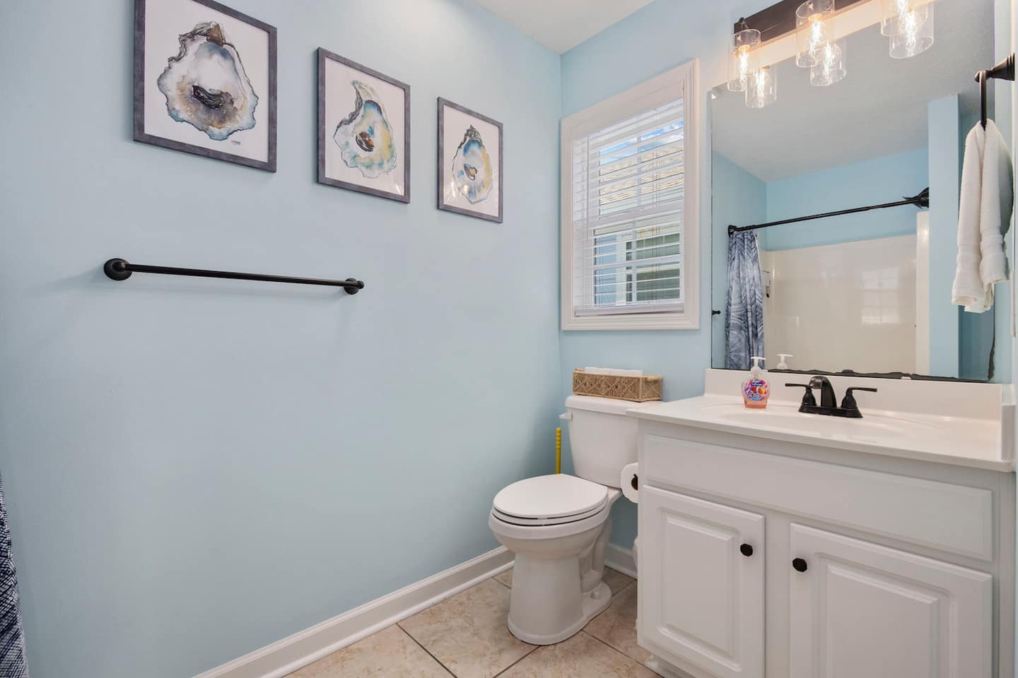 Rinse the sunscreen off in your private bathroom. Shower, tub, vanity with black fixtures, oyster watercolor prints on the wall, and a robe hanging ready.