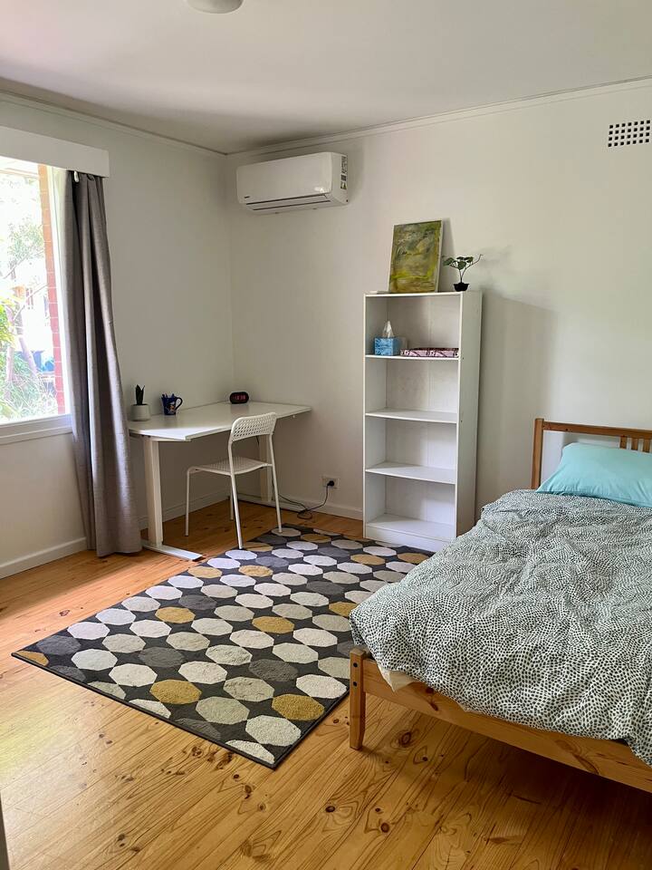 เตียงเดี่ยว โต๊ะทำงาน และเครื่องปรับอากาศ