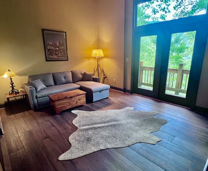 Lower living area with gas remote fireplace, sofa bed, and small viewing deck overlooking waterfall 