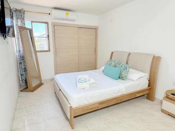 Habitación principal con baño privado, televisor y aire acondicionado