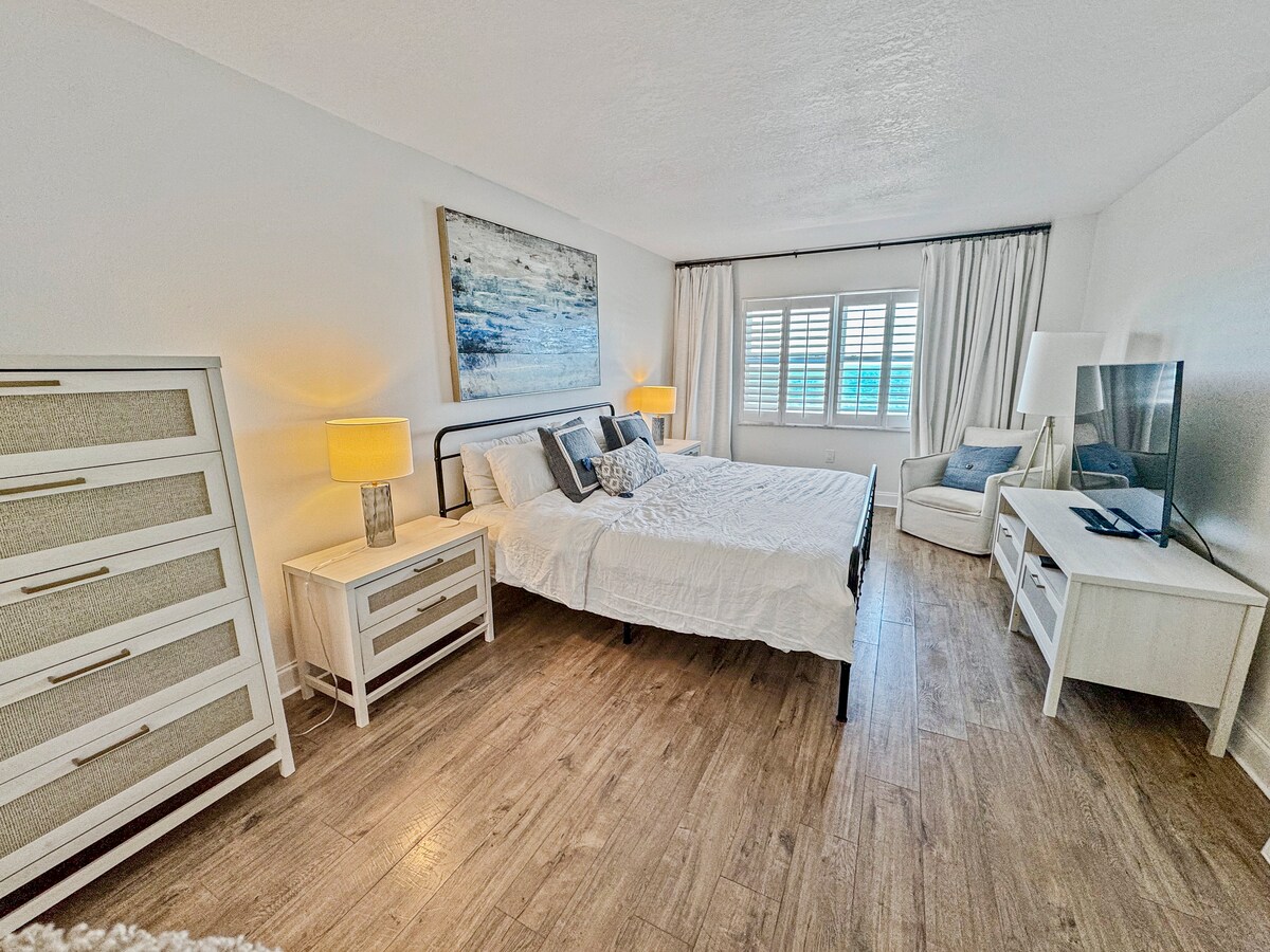 ¡Dormitorio principal con vistas al mar, persianas de plantación y cortinas opacas si lo deseas! 2 mesitas de noche, vestidor, TV con acceso a todos los canales. 