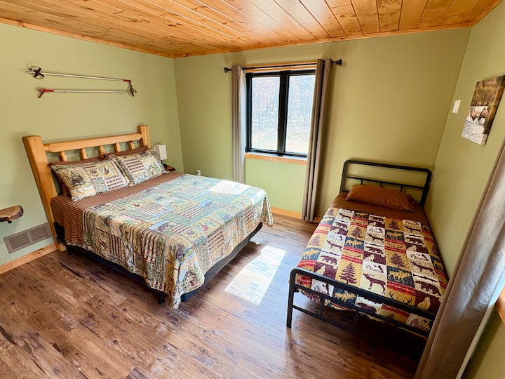 Main level bedroom with one queen bed and one twin bed. 