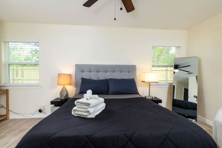 Primary bedroom featuring a plush tufted headboard, navy bedding, and plenty of natural light.