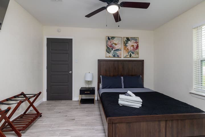 Stylish second bedroom with dark wood furniture, black bedding, and a convenient luggage rack.
