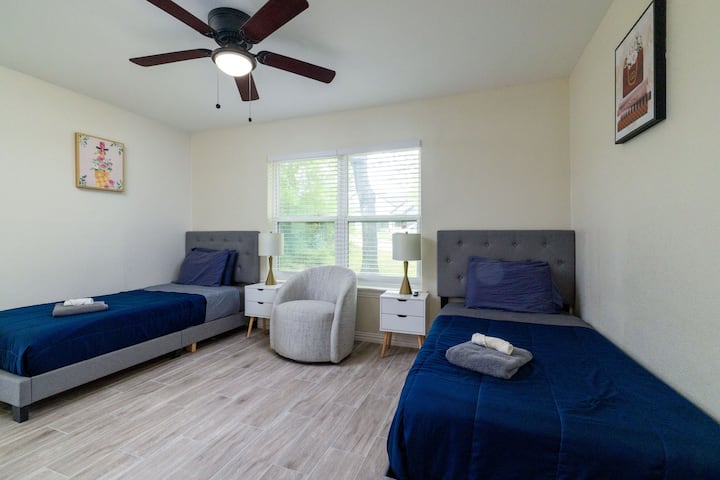 Cozy fourth bedroom featuring two twin beds, stylish decor, and a dedicated reading nook.