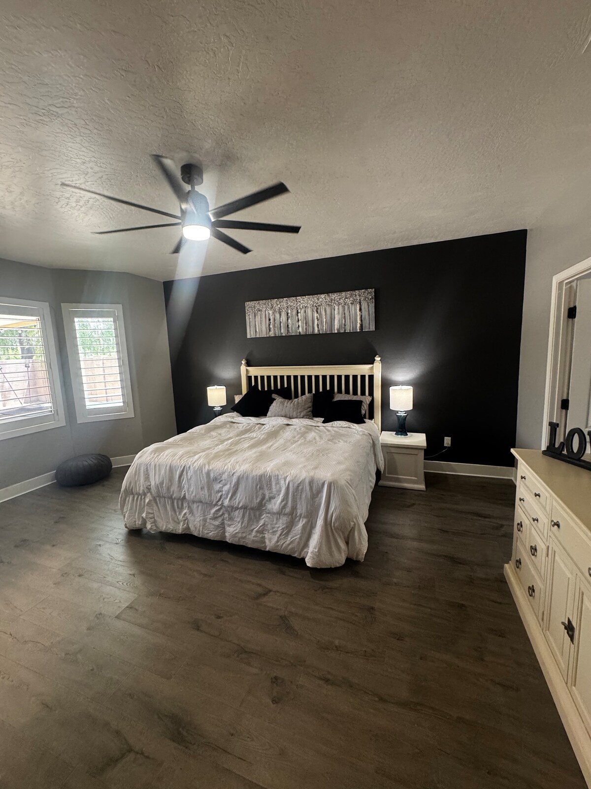 Голема главна спална соба со ѕид со медиуми и камин. Спалната соба има ролетни за приватност и има голем вентилатор на таванот. 