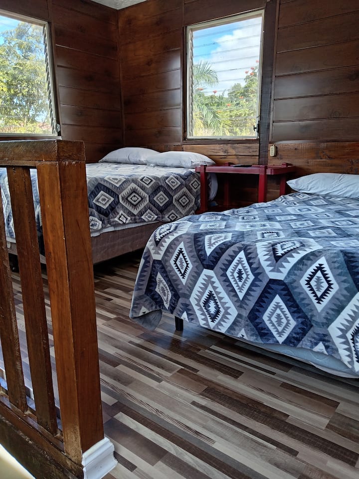 habitación con  dos camas matrimoniales, televisión, ventilador, terraza privada.
