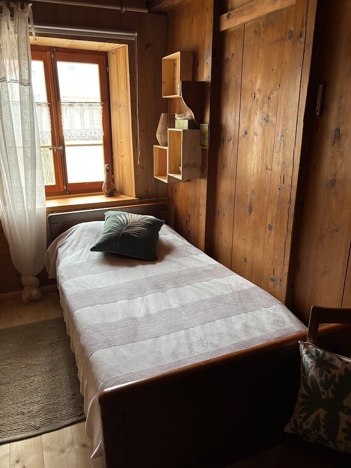 غرفة نوم صغيرة مريحة مصنوعة بالكامل من الخشب مع سرير فردي