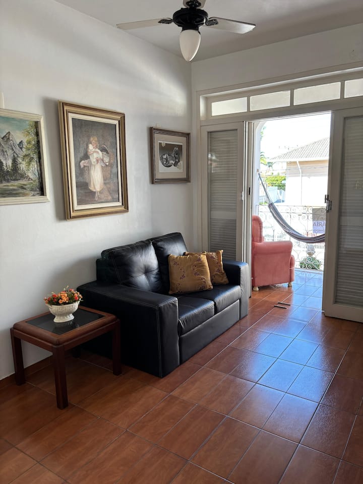 дневна соба со кауч, трпезариска маса, паметен телевизор од 40 инчи, тавански вентилатор пред балкон со поглед кон улицата.