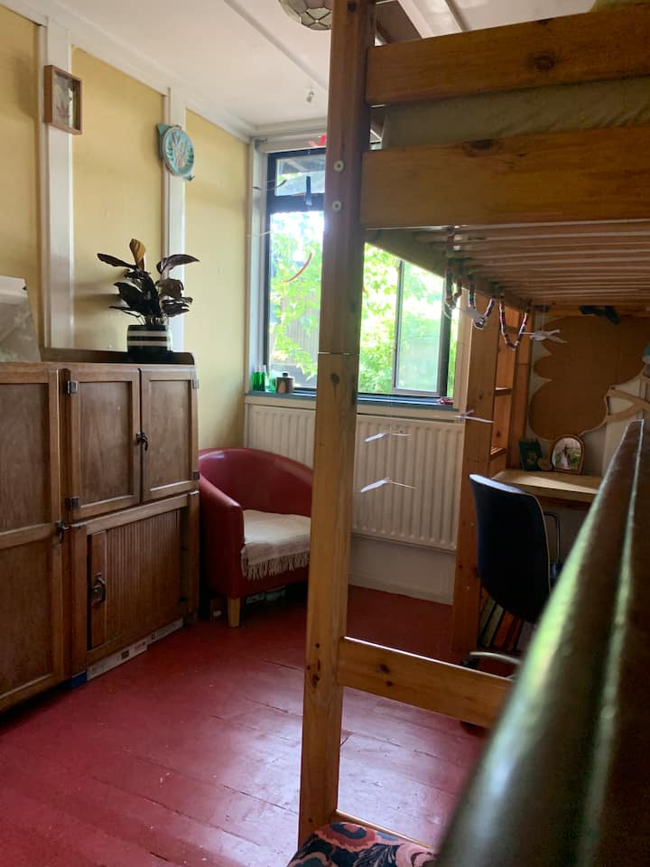 Cama loft individual con espacio de escritorio apto para trabajar debajo y persianas que oscurecen la habitación.