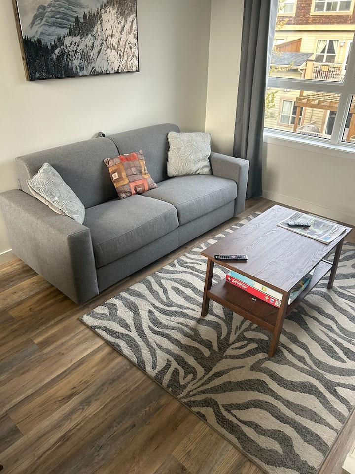 พื้นที่นั่งเล่นทันสมัยพร้อมโซฟาสบาย ๆ สมาร์ททีวี และวิวภูเขา — เหมาะสำหรับการผ่อนคลาย