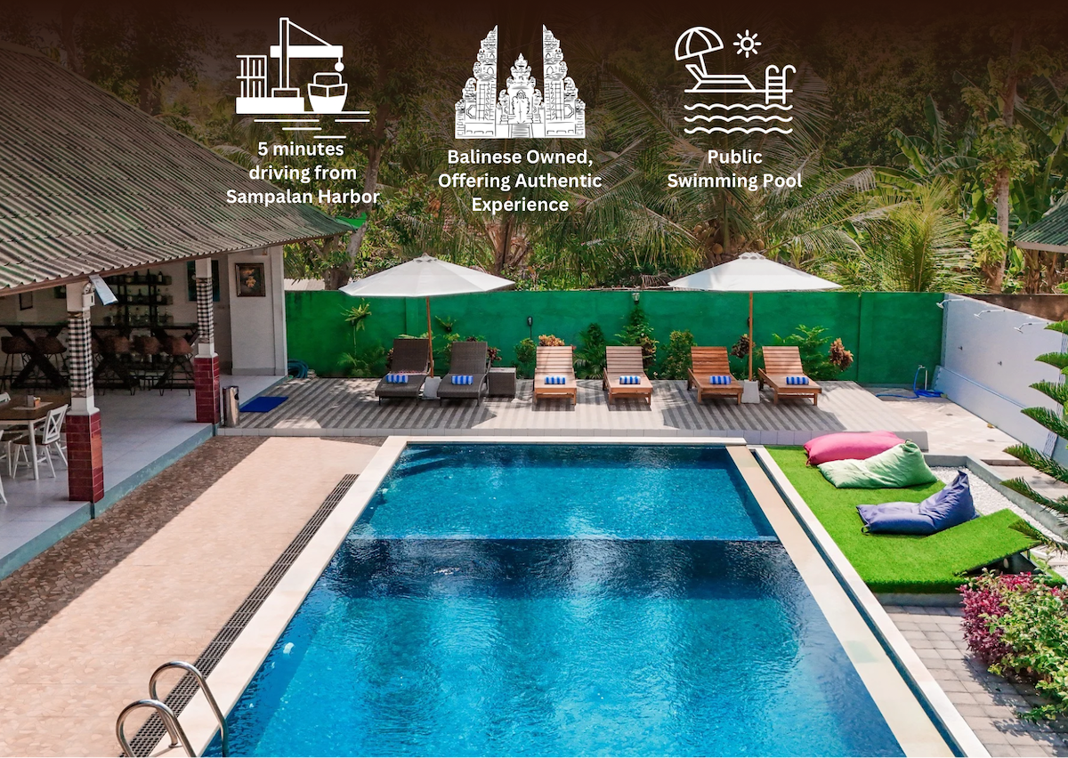A serene swimming pool is centrally located among lounge chairs, providing a relaxing atmosphere. Colorful cushions are placed on the surrounding deck. Lush greenery and a vibrant wall create a tranquil backdrop, enhancing the space's inviting nature and connection to the tropical environment.