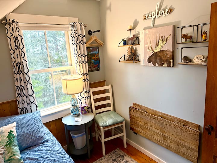 El acogedor dormitorio del segundo piso con cama matrimonial y escritorio plegable hecho a medida con una de las persianas originales de la cabaña.