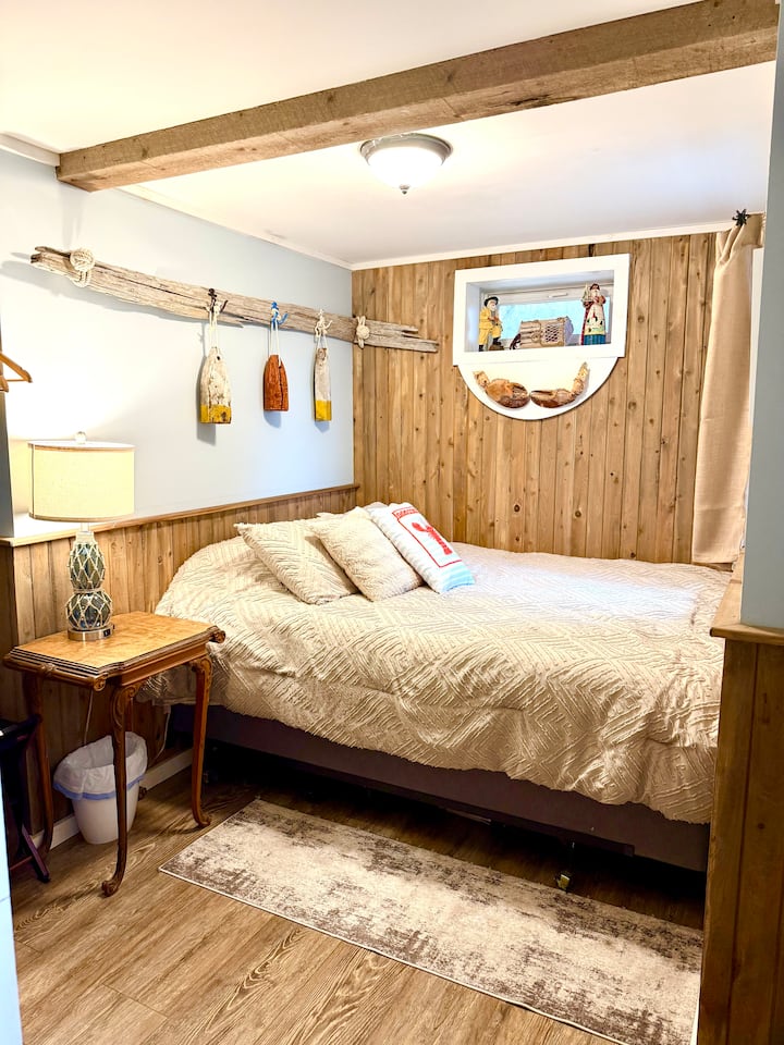 El dormitorio del sótano con acceso al exterior tiene una cama tamaño queen, un escritorio antiguo y vistas al agua.
