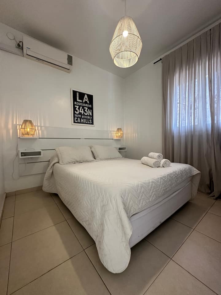 غرفة واسعة بسرير بحجم كوين وستائر خشبية سوداء ومخمل ومنافذ تحت طاولات الإضاءة ومريحة مع الأدراج. أغطية الأسرة والمناشف.