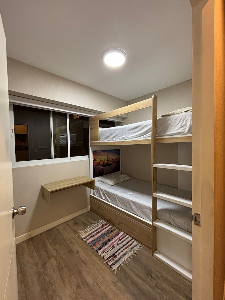 Praktična i udobna️ soba s drvenim krevetom na kat, idealna za male grupe, obitelji ili putnike koji traže udobnost u zajedničkom smještaju. U sobi se nalazi sklopivi radni stol, prozor s dobrim osvjetljenjem i ukrasni detalji koji unose toplinu.