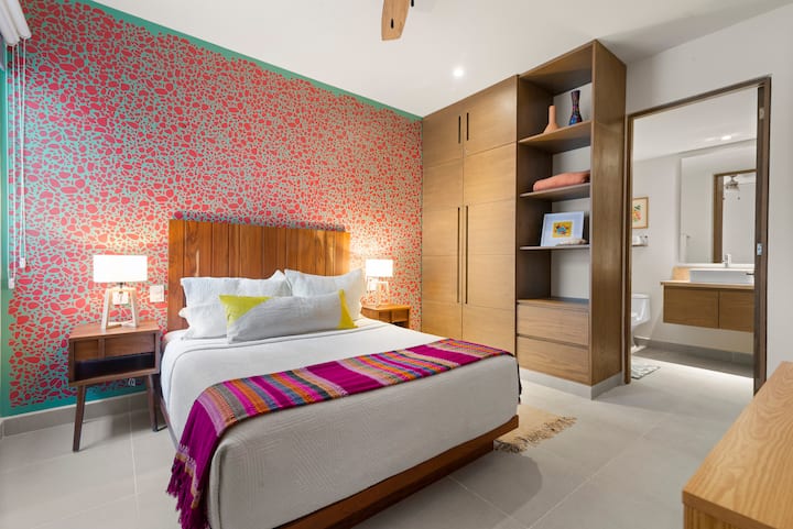 Habitación acogedora con cama queen, lámparas de noche e interruptores de luz y tomacorrientes de fácil acceso. Disfrute de aire acondicionado, un ventilador de techo, persianas opacas y su propio baño privado para una estadía cómoda y relajante.