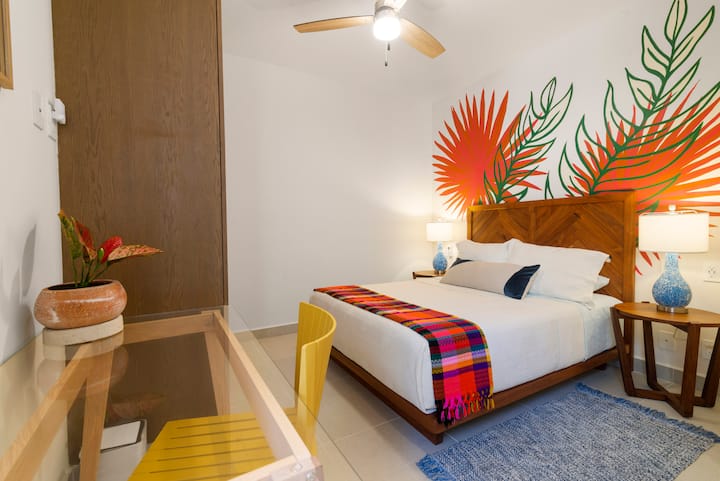 Habitación cómoda con cama queen, escritorio para trabajar a distancia y lámparas de noche a cada lado. Disfrute de interruptores de luz y tomacorrientes de fácil acceso, además de aire acondicionado y un ventilador de techo para una estancia fresca y relajante.
