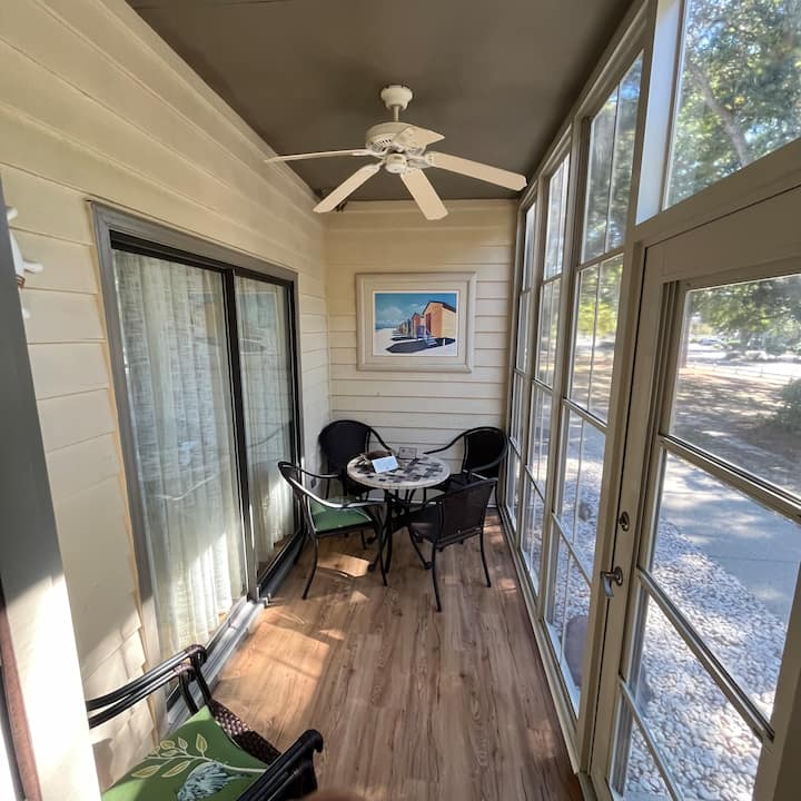 Პატარა მზის ოთახი საუზმის მაგიდით და 6 ადამიანისთვის განკუთვნილი ჯდომით. Უკანა კარი ეზოსკენ, გასრიალებული კარები საძინებლისკენ და კარი მისაღები ოთახისკენ.