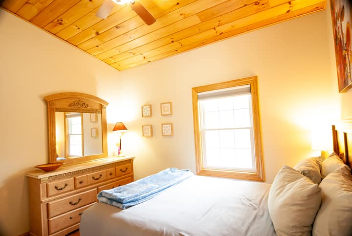 This second floor bedroom provides a queen size bed with extra fluffy pillows, a Roku TV and overhead fan for comfort.