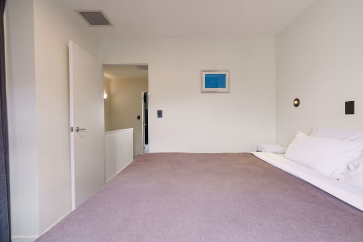 温馨、简约的卧室等待着您！ 在一天的探索后，清爽的白色床单和舒缓的薰衣草被子为您提供了完美的休憩之处。 明亮、干净，为您的城市度假做好准备。 管道空调系统，立即预订您的休闲住宿！