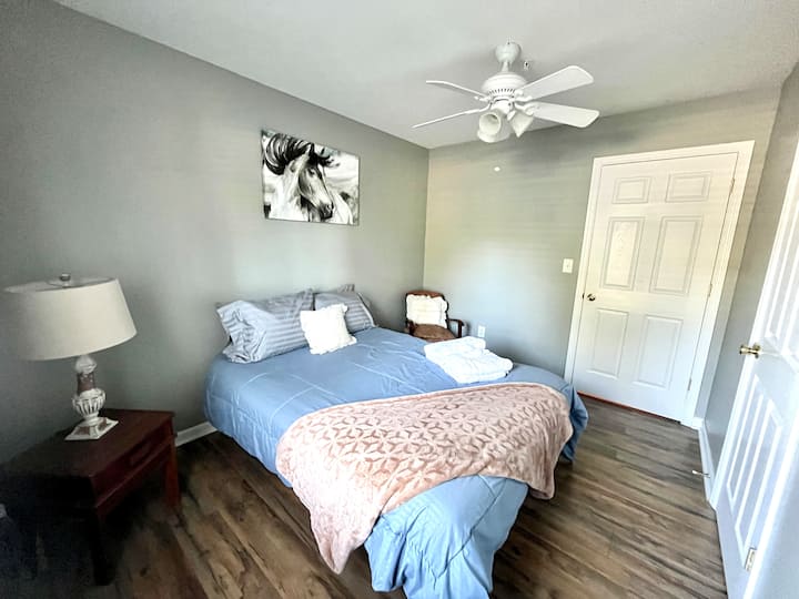 Cozy gray bedroom with soft bedding, ceiling fan, and warm wood floors