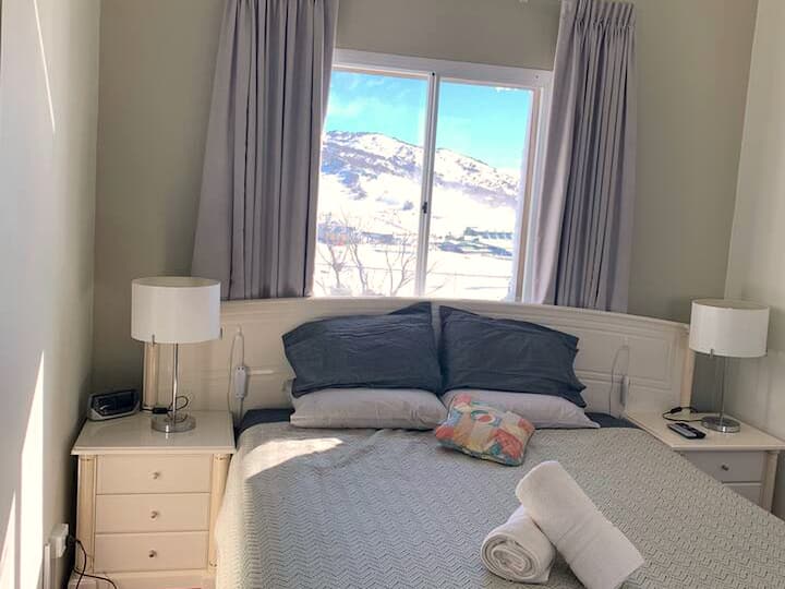 Chumba cha kulala chenye starehe kilicho na matandiko bora, meza za kando ya kitanda na mwanga mchangamfu kwa ajili ya usingizi wa usiku wa kupumzika. Chumba cha kulala chenye mandhari ya theluji, kinachounganisha starehe na mandhari ya milima