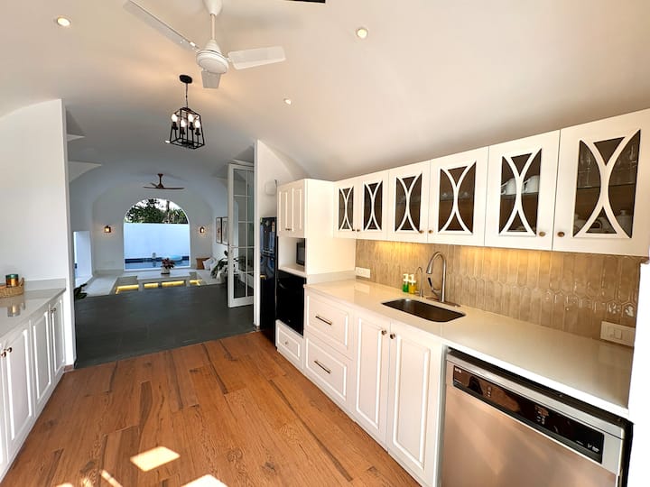 This elegant white European-style kitchen is thoughtfully designed with all modern appliances, gener