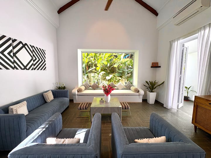 A grand, beautifully designed living room blending Santorini elegance with Goa luxury, offering gene