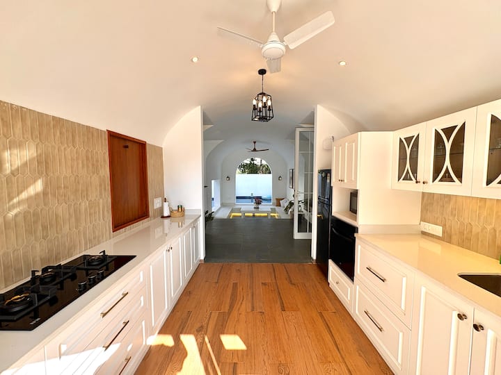 A spacious, sunlit white European-style kitchen equipped with modern appliances, sleek finishes, and