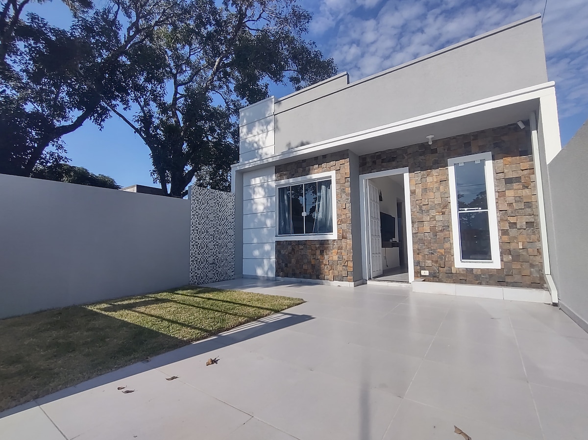 A modern exterior showcases a well-maintained facade with a mix of stone and smooth surfaces. Large windows allow for ample natural light, and a grassy area beside the paved entrance enhances the outdoor space. A clear sky complements the property's inviting appearance.
