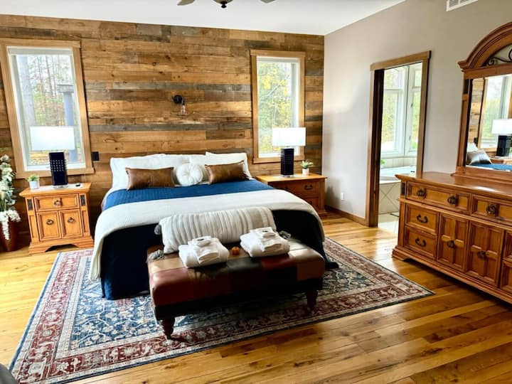 Bedroom 1: Main level primary room with jacuzzi tub, private bath, attached nursery, fireplace, and deck access.
