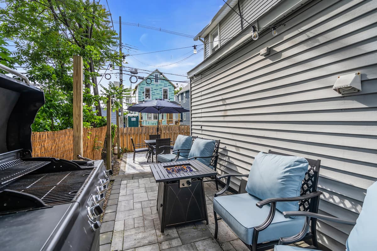 The new patio at dusk with fire pit, string lights and seating for four
